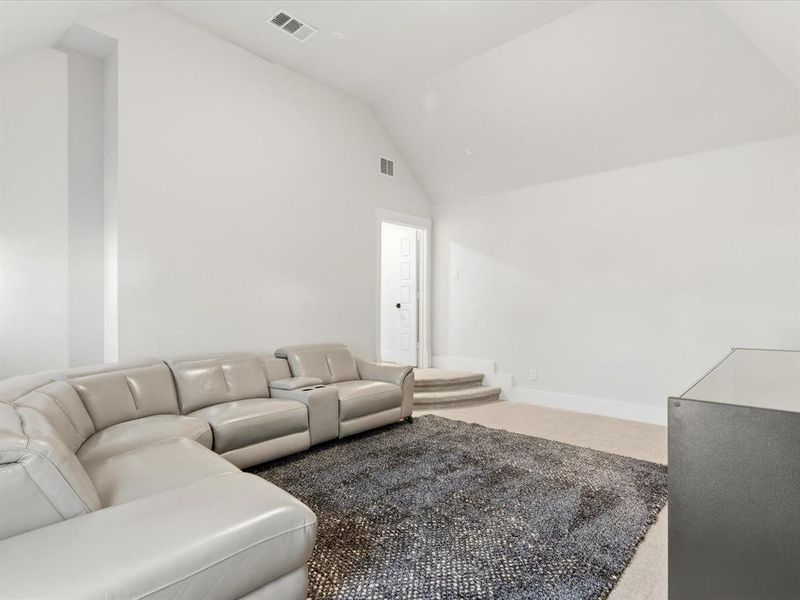 Spacious room featuring a vaulted ceiling, neutral wall tones, and plush carpet flooring Spacious room featuring a vaulted ceiling, neutral wall tones, and plush carpet flooring