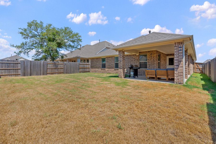 Rear view of house with a fenced backyard, a patio, brick siding, and an outdoor living space Rear view of house with a fenced backyard, a patio, brick siding, and an outdoor living space