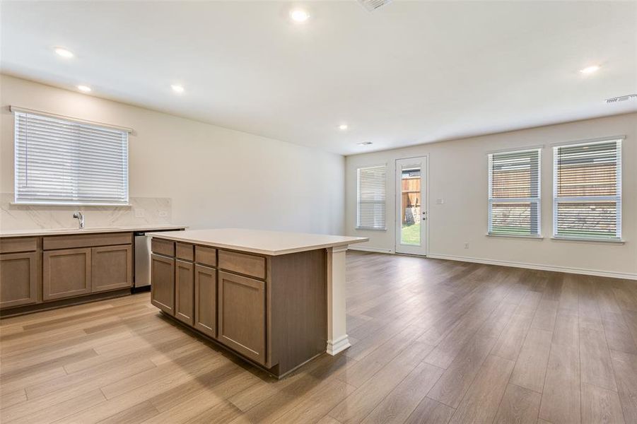 Kitchen featuring open floor plan, backsplash, recessed lighting, a kitchen island, and light wood-type flooring Kitchen featuring open floor plan, backsplash, recessed lighting, a kitchen island, and light wood-type flooring