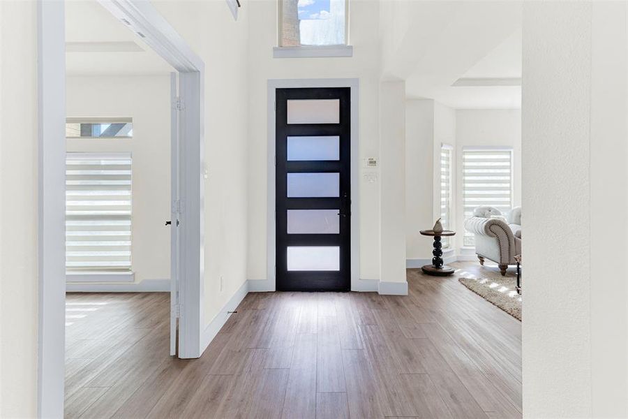 Foyer entrance with light wood-style flooring and a high ceiling Foyer entrance with light wood-style flooring and a high ceiling