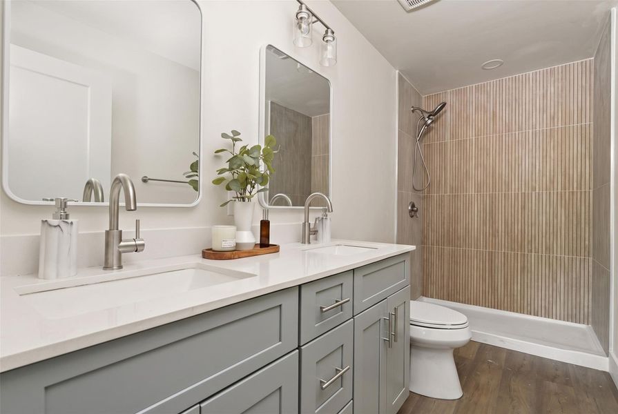 Dual vanity with pristine countertops and an elegantly tiled walk-in shower elevate this bathroom.