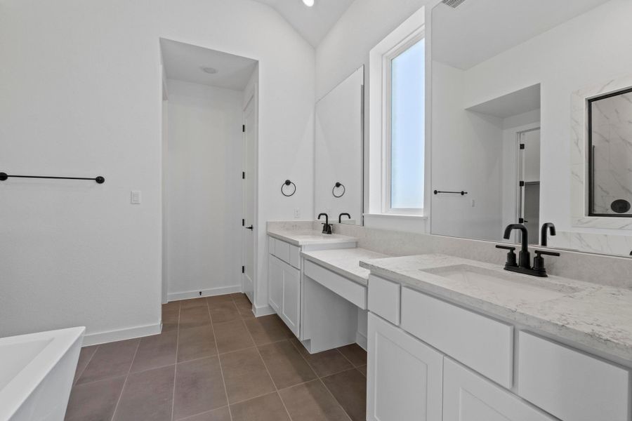 Bathroom featuring two vanities, a bathtub, tile patterned floors, and a marble finish shower
