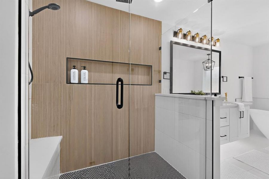 Spacious walk-in shower featuring a glass enclosure with matte black hardware, textured wood-finish wall tile, a built-in shower niche, and a contrasting black and white mosaic tile floor