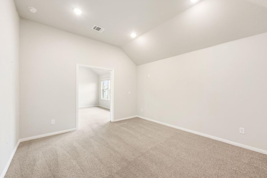 Empty bedroom with vaulted ceiling, recessed lighting, and beige carpet flooring Empty bedroom with vaulted ceiling, recessed lighting, and beige carpet flooring