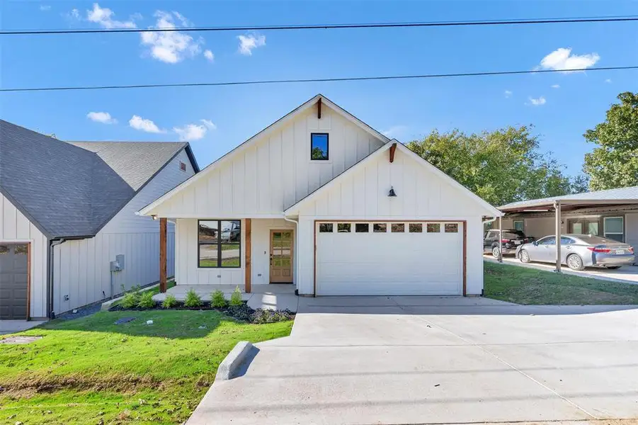 Modern farmhouse featuring board and batten siding, a front yard, driveway, and covered porch