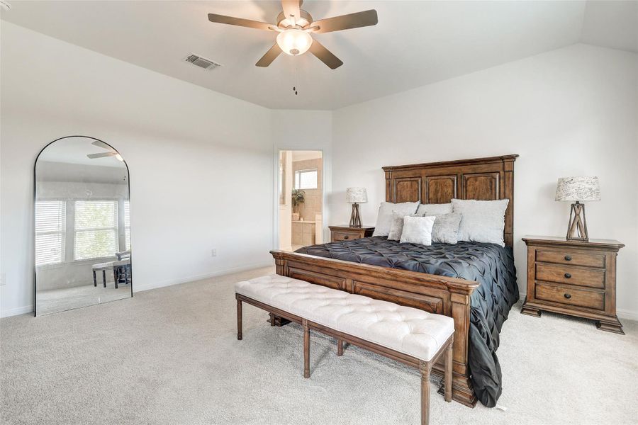 Bedroom featuring light carpet, ceiling fan, connected bathroom, and lofted ceiling