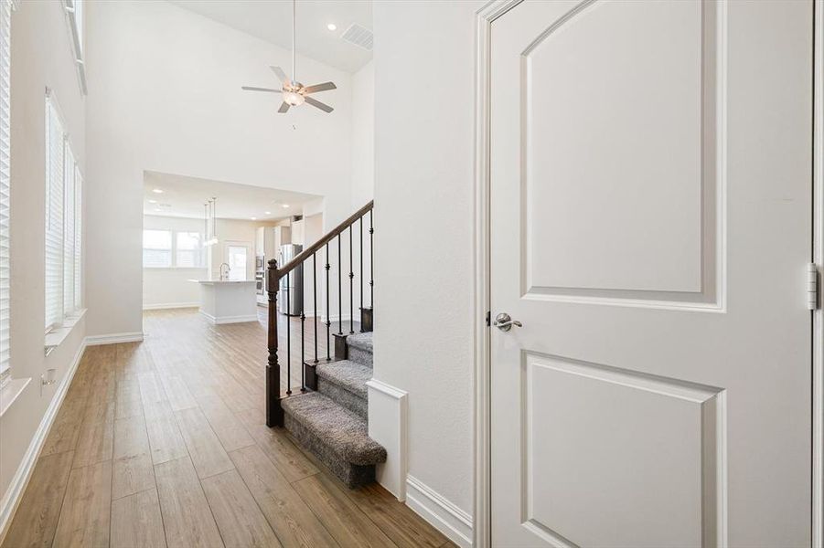 Entryway featuring ceiling fan, light hardwood / wood-style floors, and a towering ceiling