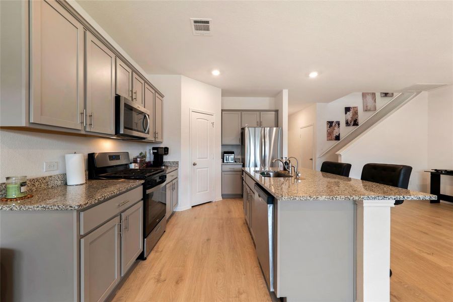 Kitchen space boasts light wood flooring and sleek cabinetry.