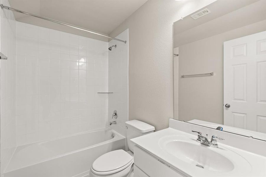 The secondary bath features tile flooring, white cabinetry and light countertops and a shower/tub combo. Perfect for accommodating any visiting family and friends.