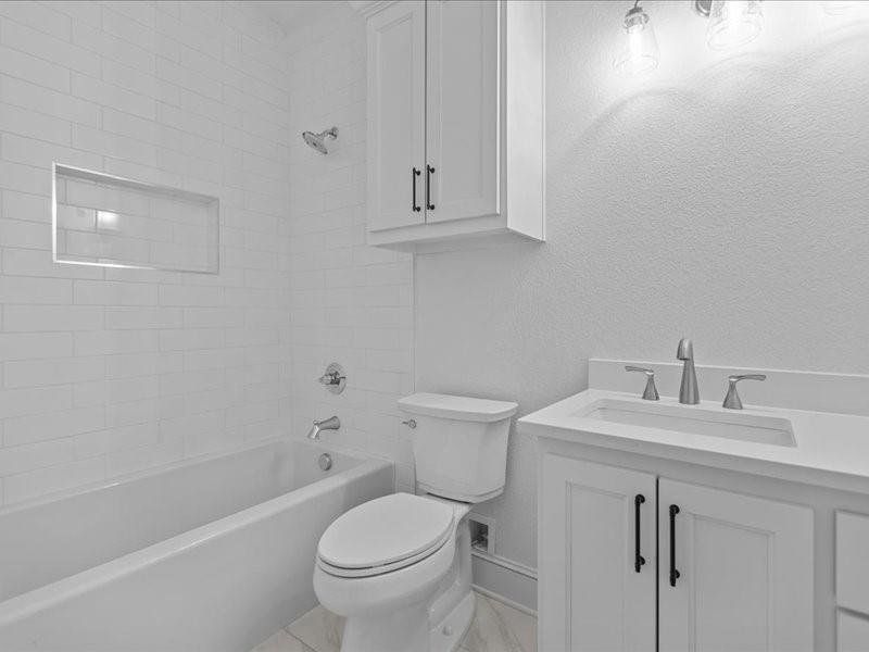 Full bath featuring vanity,  shower combination, and a textured wall