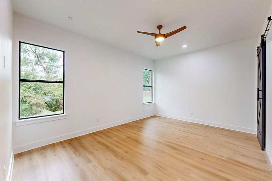Bright interior room featuring wood-finish flooring, recessed lighting, and a contemporary ceiling fan Bright interior room featuring wood-finish flooring, recessed lighting, and a contemporary ceiling fan