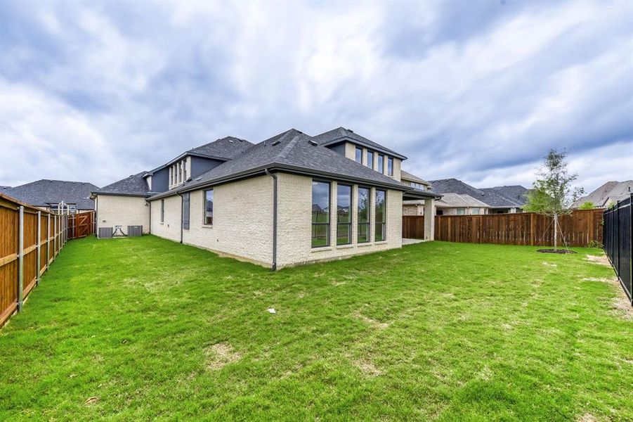 Back of house with brick siding, a fenced backyard, a patio area, and a shingled roof