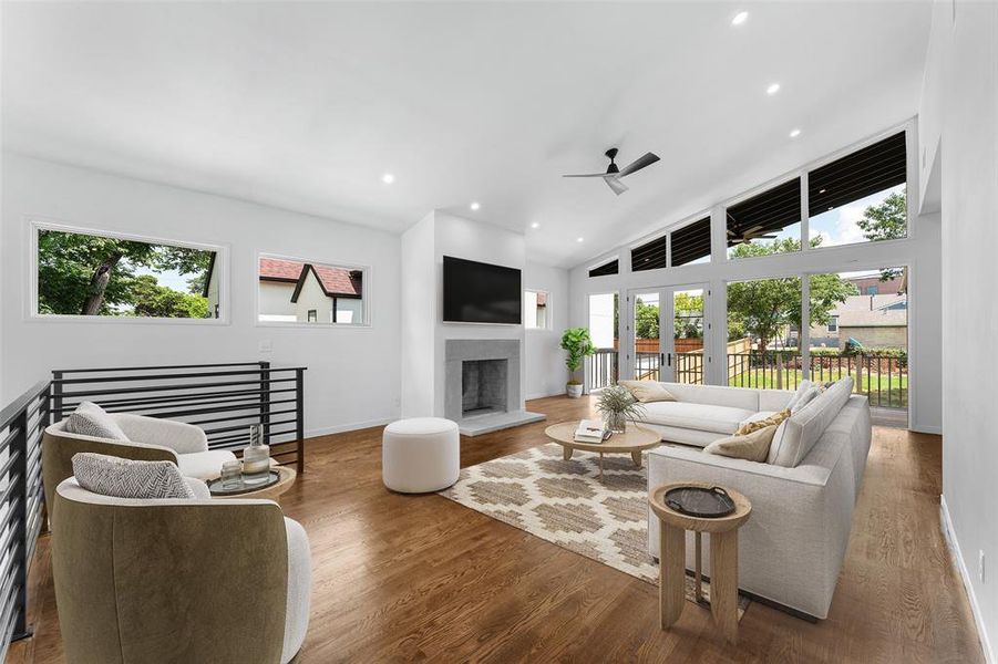 Living room featuring a ceiling fan, wood finished floors, recessed lighting, a fireplace with raised hearth, and high vaulted ceiling