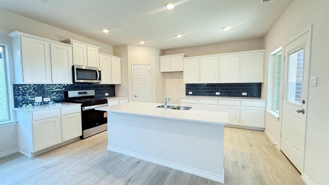 Kitchen with white cabinetry, appliances with stainless steel finishes, tasteful backsplash, an island with sink, and recessed lighting