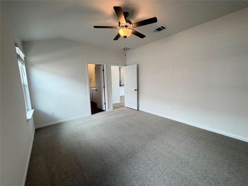 Unfurnished bedroom with carpet, lofted ceiling, connected bathroom, and a ceiling fan