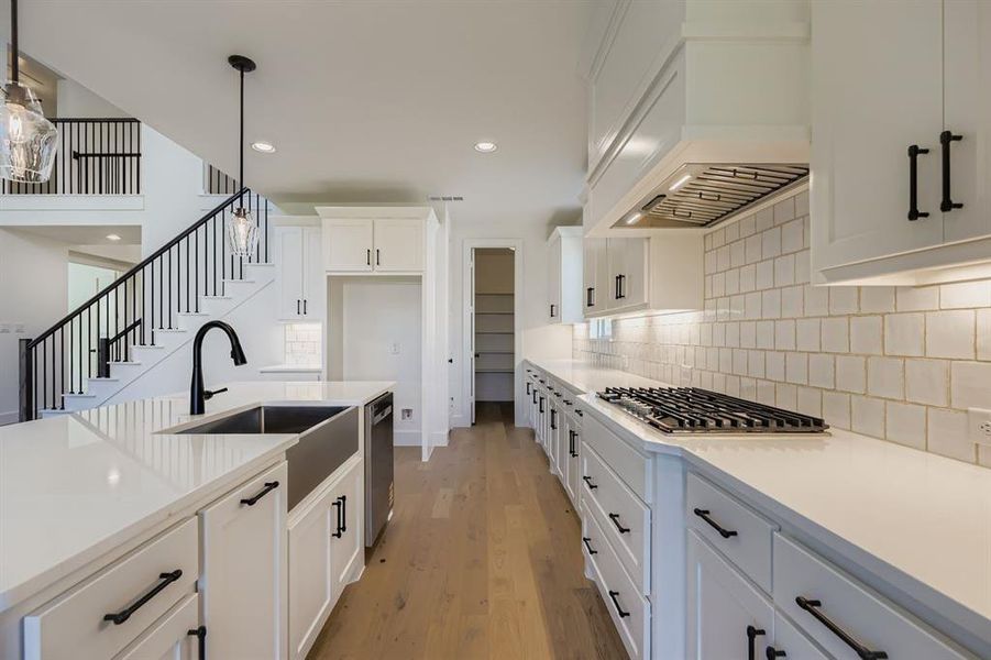 Kitchen with white cabinetry, light wood finished floors, backsplash, pendant lighting, and recessed lighting
