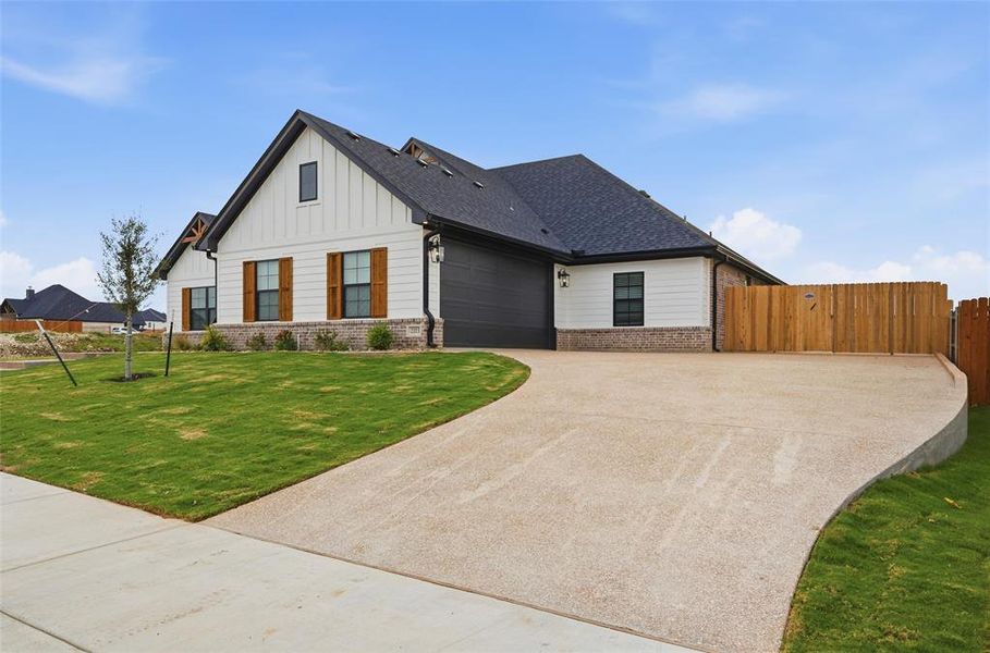Modern farmhouse featuring brick siding, board and batten siding, concrete driveway, and an attached garage Modern farmhouse featuring brick siding, board and batten siding, concrete driveway, and an attached garage