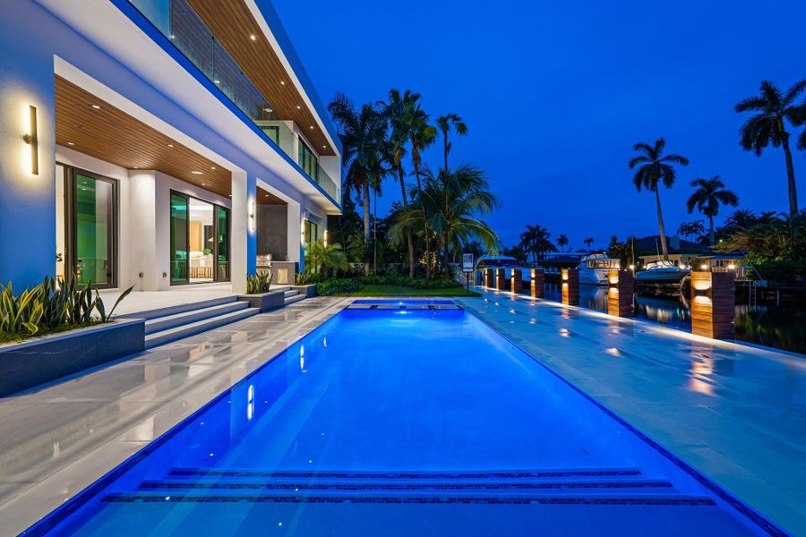 Resort-style waterfront living with a glowing pool, lush palms, and dramatic twilight views over the canal. Resort-style waterfront living with a glowing pool, lush palms, and dramatic twilight views over the canal.