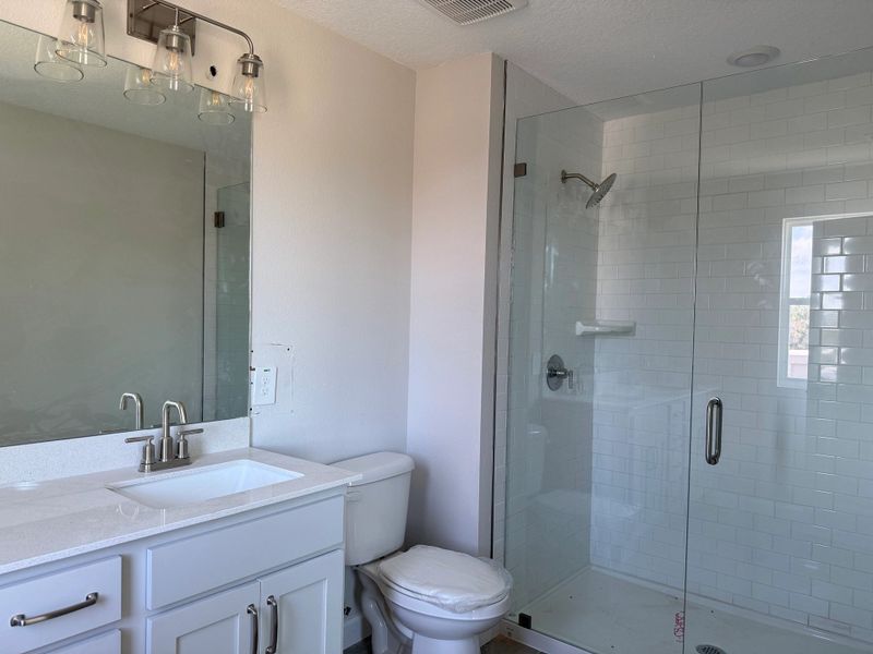 Luxurious primary bath with dual vanities and frameless glass shower, featuring the AW Milan Collection Luxurious primary bath with dual vanities and frameless glass shower, featuring the AW Milan Collection