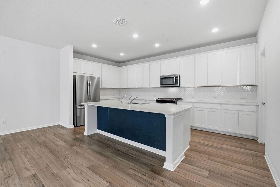 A contemporary kitchen features bright white cabinetry and a striking blue island, complemented by sleek stainless steel appliances. A contemporary kitchen features bright white cabinetry and a striking blue island, complemented by sleek stainless steel appliances.