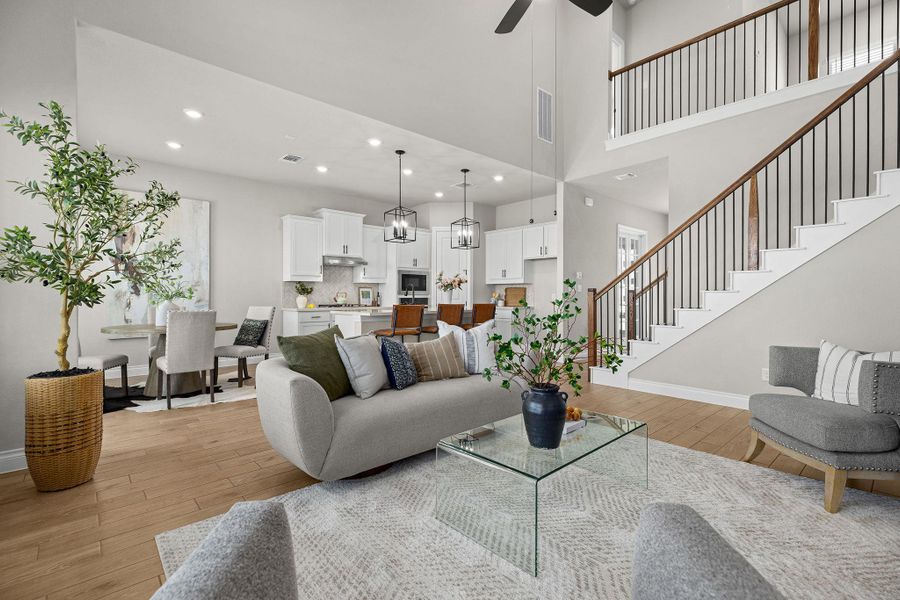 Living area featuring light wood-style floors, recessed lighting, ceiling fan, a towering ceiling, and a chandelier