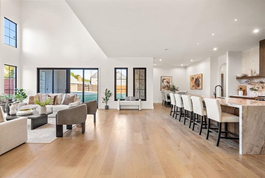 Living area with light wood-type flooring, recessed lighting, arched walkways, and a high ceiling Living area with light wood-type flooring, recessed lighting, arched walkways, and a high ceiling