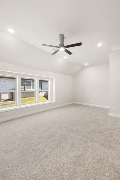 Empty bedroom with vaulted ceiling, ceiling fan, carpet flooring, and large windows