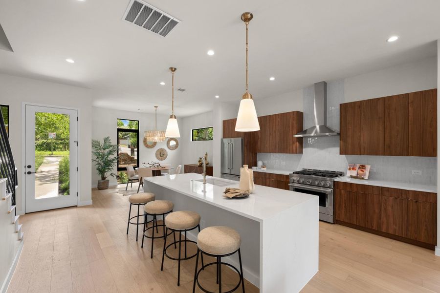 A spacious, naturally illuminated kitchen and dining area features modern cabinetry and an expansive center island. A spacious, naturally illuminated kitchen and dining area features modern cabinetry and an expansive center island.