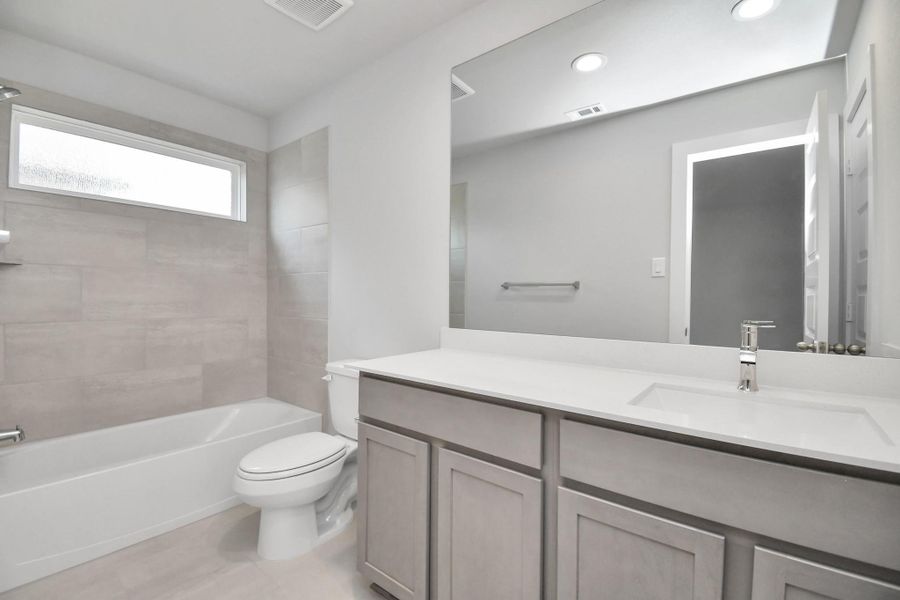 Secondary bath features tile flooring, bath/shower combo with tile surround, light stained wood cabinets, beautiful light countertop. Secondary bath features tile flooring, bath/shower combo with tile surround, light stained wood cabinets, beautiful light countertop.