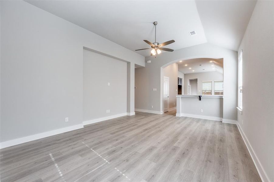 Unfurnished living room featuring ceiling fan, light wood-style floors, lofted ceiling, recessed lighting, and arched walkways