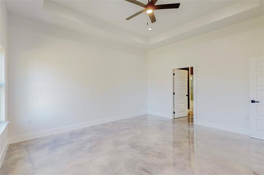 Spare room with ceiling fan, concrete flooring, and a raised ceiling