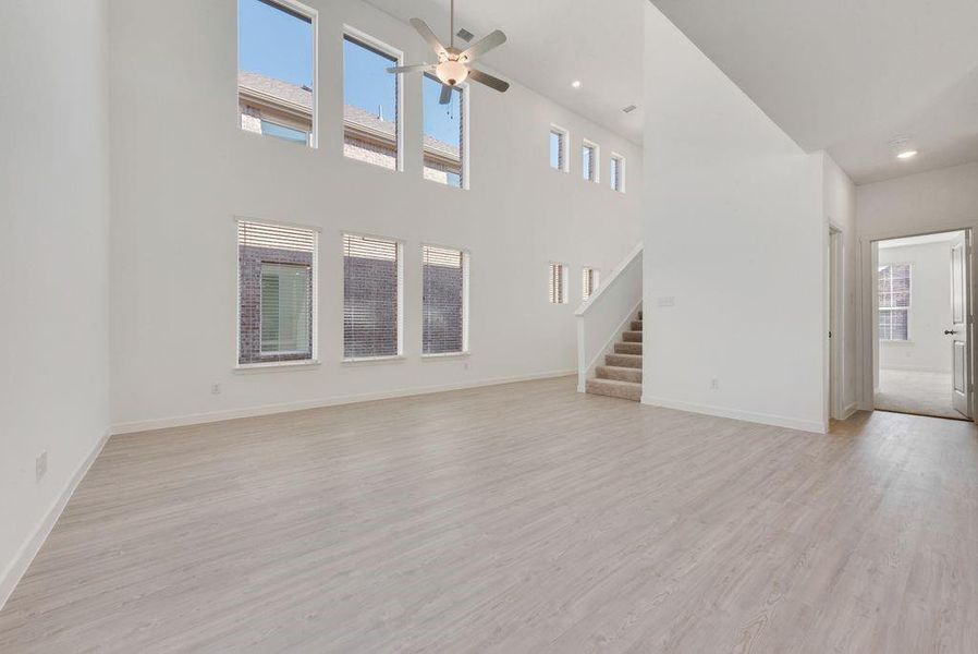 Unfurnished living room featuring stairs, light wood-type flooring, ceiling fan, and healthy amount of natural light Unfurnished living room featuring stairs, light wood-type flooring, ceiling fan, and healthy amount of natural light