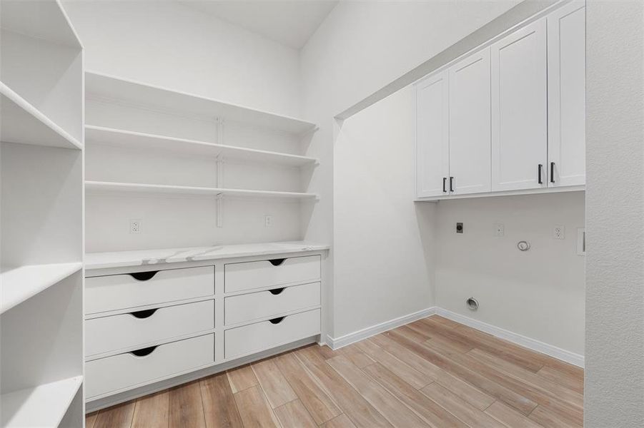 Washroom featuring cabinet space, light wood-type flooring, hookup for an electric dryer, and hookup for a gas dryer