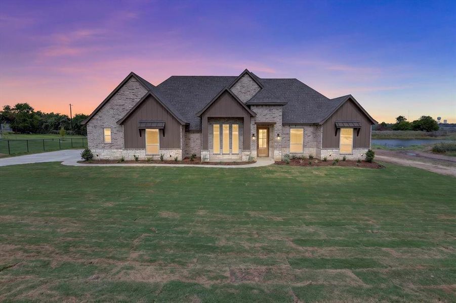 Stone and brick exterior featuring dark wood siding accents, a dark shingle roof, and a covered entryway Stone and brick exterior featuring dark wood siding accents, a dark shingle roof, and a covered entryway