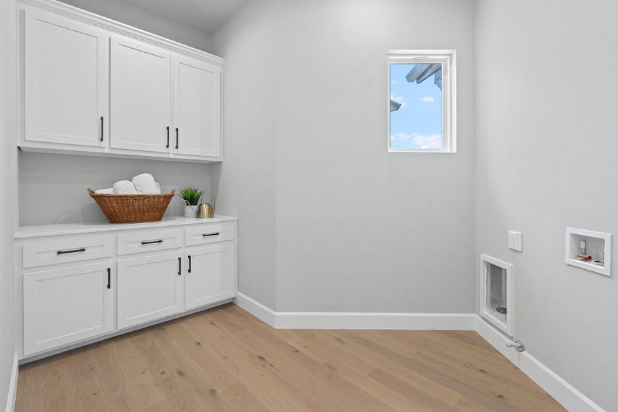 Laundry room featuring cabinet space, hookup for a washing machine, and light wood-style flooring