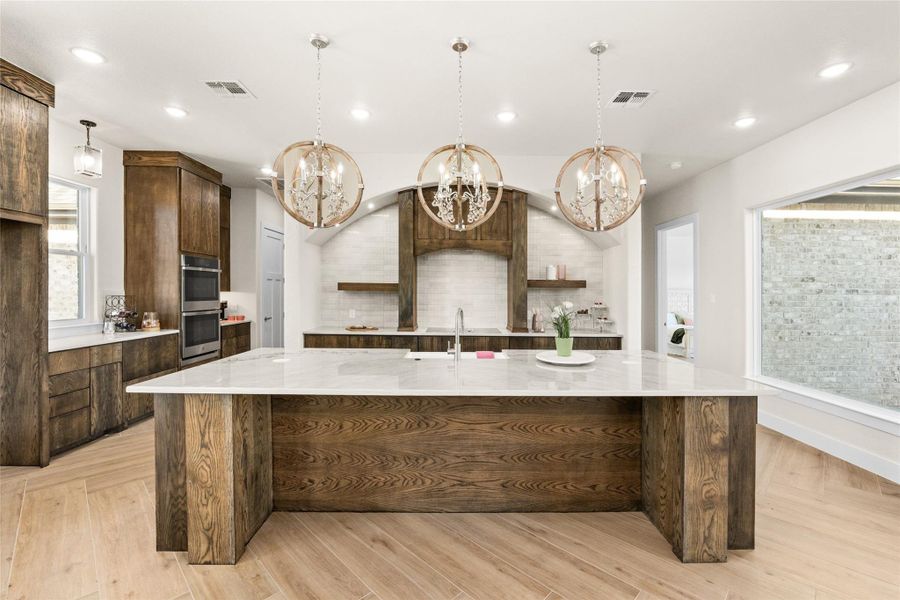 Kitchen featuring pendant lighting, modern cabinets, open shelves, a large island, and light stone counters