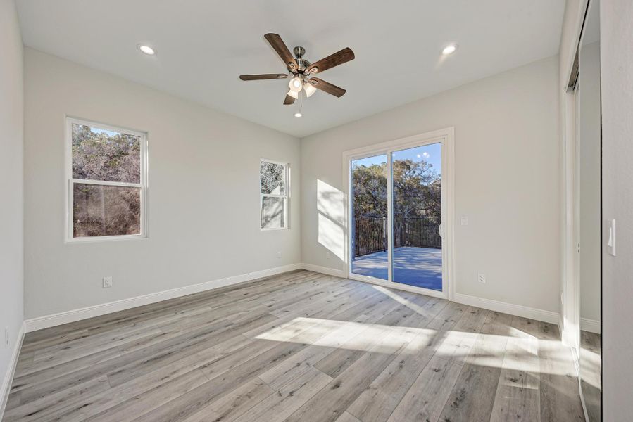 Empty room featuring light wood-type flooring, ceiling fan, recessed lighting, and plenty of natural light