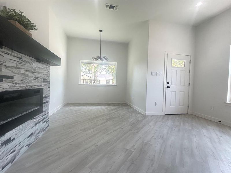 Unfurnished living room featuring light hardwood / wood-style floors, a notable chandelier, and a high ceiling