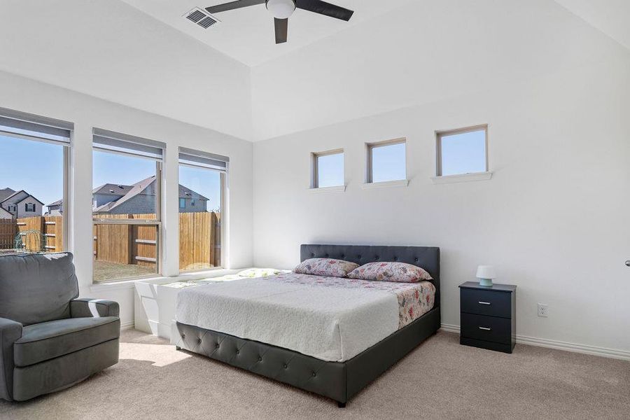 Bedroom with carpet flooring, a ceiling fan, and vaulted ceiling Bedroom with carpet flooring, a ceiling fan, and vaulted ceiling