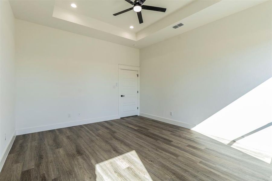 Spare room with a tray ceiling, dark hardwood / wood-style flooring, and ceiling fan