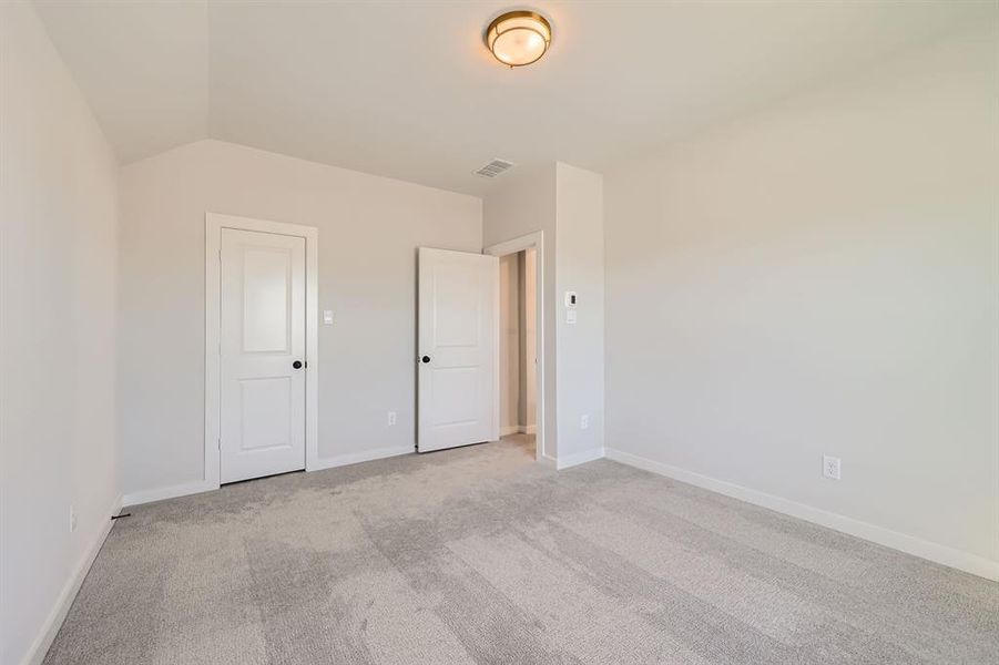 Carpeted empty room featuring vaulted ceiling