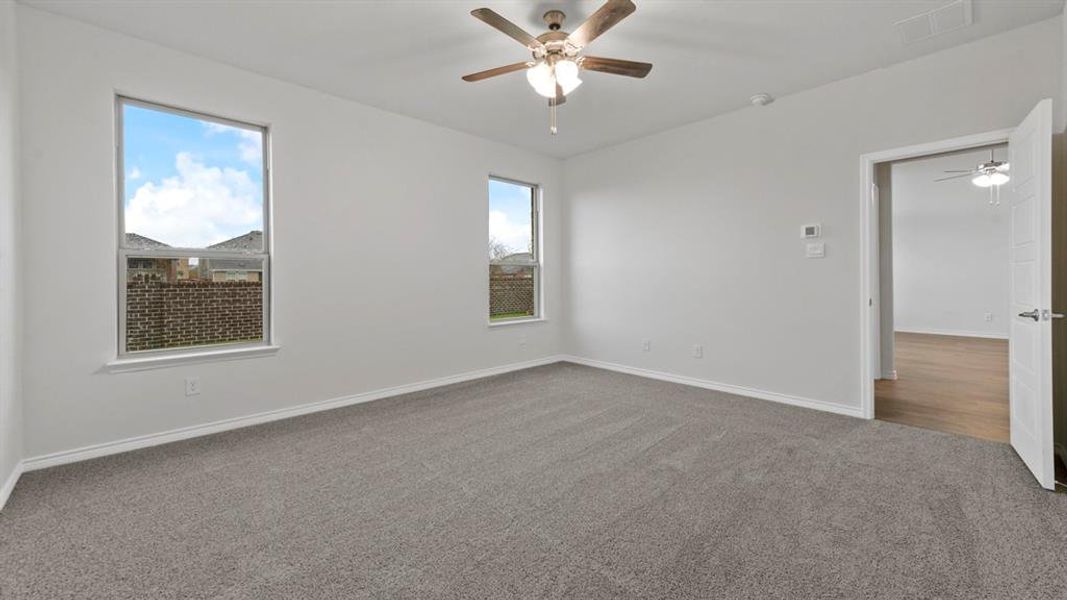 Carpeted empty room with ceiling fan and baseboards Carpeted empty room with ceiling fan and baseboards