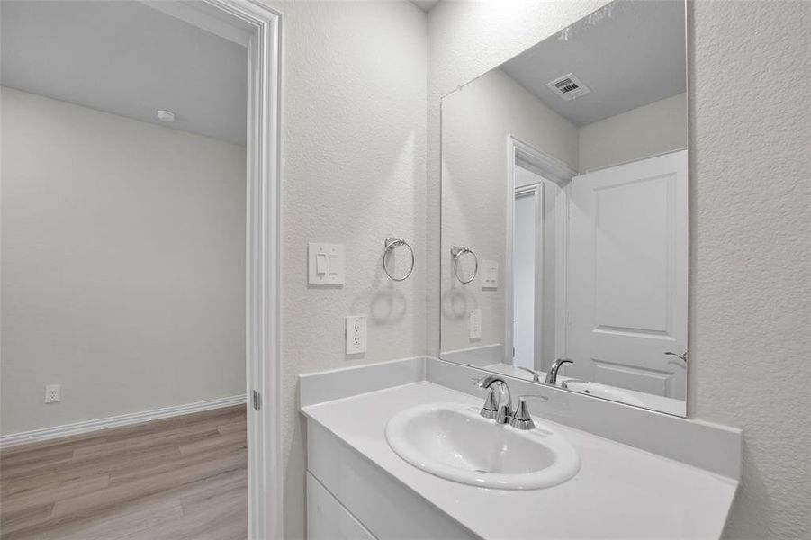 Bathroom with a textured wall, vanity, and light wood-style flooring Bathroom with a textured wall, vanity, and light wood-style flooring