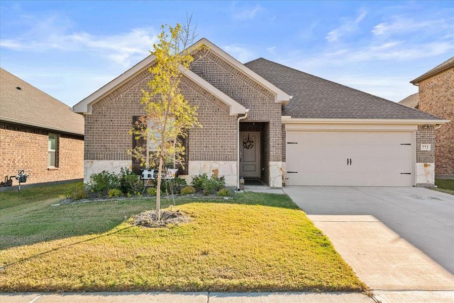 View of front facade featuring a garage and a front lawn