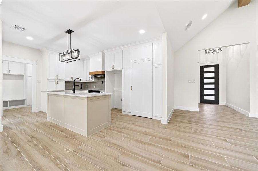 Open-concept kitchen featuring an island with a contrasting base, white cabinetry, and wood-finish flooring Open-concept kitchen featuring an island with a contrasting base, white cabinetry, and wood-finish flooring