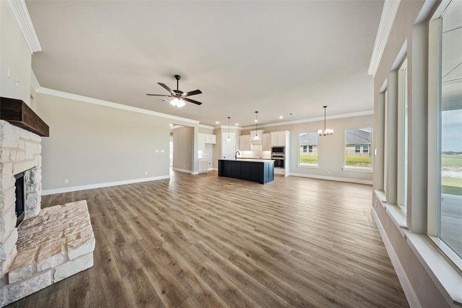Unfurnished living room featuring a stone fireplace, a ceiling fan, wood finished floors, crown molding, and recessed lighting Unfurnished living room featuring a stone fireplace, a ceiling fan, wood finished floors, crown molding, and recessed lighting