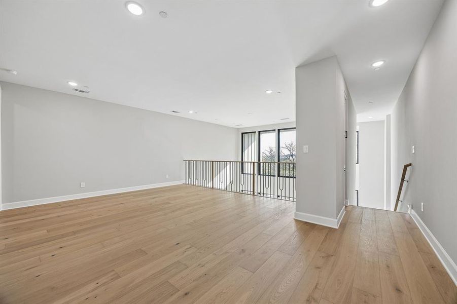 Empty room featuring light wood-style flooring, expansive windows, and recessed lighting Empty room featuring light wood-style flooring, expansive windows, and recessed lighting