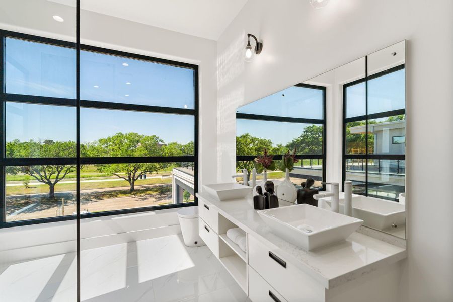 This expansive primary bath offers dual sinks situated in a stunning floating vanity in addition to extra shelving and drawer space offering added organization.