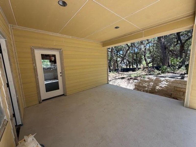 A spacious covered patio invites outdoor enjoyment, overlooking a natural, treed landscape with a stone retaining wall. A spacious covered patio invites outdoor enjoyment, overlooking a natural, treed landscape with a stone retaining wall.