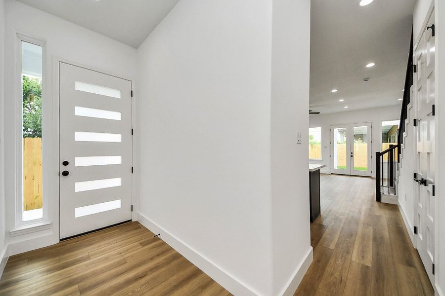 Clean and inviting front entryway featuring a modern statement door, sleek finishes, and warm wood flooring that sets the tone for the home’s contemporary design. A bright, welcoming space that creates a strong first impression from the moment you step inside.